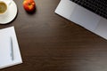 Desk in the office with a notebook next to an apple and cup of c