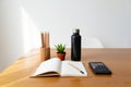 Desk with open notebook, pencil, calculator, water bottle and small plant, organized workspace setup Royalty Free Stock Photo