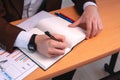 Desk with papers, graphs, a white pad and the hands of a businessman who is about to write. Close-up to the hands of a man Royalty Free Stock Photo