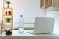 Desk in the room with a laptop and a bottle of water