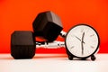 clock on desk side by side with dumbbells for exercise during work time fitness concept