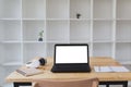 Desk table with laptop, headphone, notepad with white bookshelf