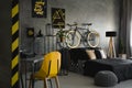 Desk with typewriter in dark room interior with pouf and bicycle near bed. Real photo