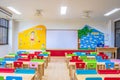 Desks, chairs and white board in the kindergarten classroom. And there are beautifully decorated knowledge boards