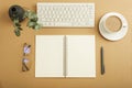 Desktop with blank notepad, keyboard, glasses and coffee cup on brown table. Top view, flat lay