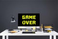 desktop computer with game over inscription on screen, graphics tablet and office supplies