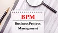 Desktop magnifier, reports, pen and notebook with text BPM Business Process Management. Business concept