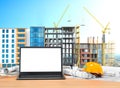 Desktop with an open laptop, construction drawings in rolls, construction helmet Royalty Free Stock Photo