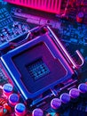 The desktop of the processor lies with the contacts up on the motherboard of a personal computer. Illuminated with blue neon light
