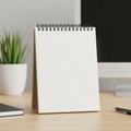 A desktop scene featuring a spiral-bound blank notepad standing on a wooden Royalty Free Stock Photo