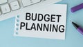 On the desktop there are reports, notepads, a calculator, a cash and a yellow sticker with the text BUDGET PLANNING.