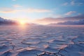 Desolate frozen desert under a pale sun. Crust of snow cracked in the wind. Clear bright sky snowy mountains on horizon Royalty Free Stock Photo