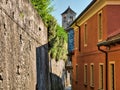 Desolate street with via and stone walls on the San GIulio Island in Lake Orta Italy with the belfry of San Giulio Basilica in the Royalty Free Stock Photo
