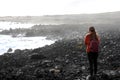 Desolate volcanic black rocks with lonely girl. Back view of young woman standing reflexive and sad on hidden rocky beach. Young Royalty Free Stock Photo