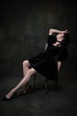 Classic retro portrait of young adorable woman in image of medieval royal person in black dress isolated on dark vintage