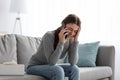 Despair upset caucasian millennial woman suffering from depression, crying and talking on phone at home