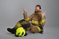 Despaired, emotional fireman raising hands, crying, while sitting on floor. Royalty Free Stock Photo