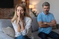 Despaired middle aged european wife suffering from quarrel, ignoring husband in living room interior