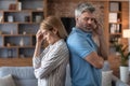 Despaired sad middle aged european male ignores offended woman in living room interior, back to back