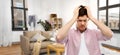 Despaired young man in messy room having headache