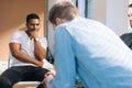 Close-up back view of depressed young man sharing mental problem sitting in circle to other patients during group Royalty Free Stock Photo