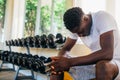 Desperate African American man sitting on bench during break in fitness training in modern gym