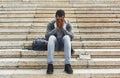 Desperate african-american student sitting on stairs outdoors