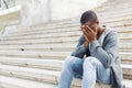 Desperate african-american student sitting on stairs outdoors