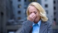 Desperate aged woman in business suit crying outdoors office building, dismissal Royalty Free Stock Photo