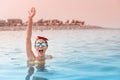 Desperate asian woman swimming in the sea and asking for help, shouts and raises her hand. Concept of accidents and drowning in Royalty Free Stock Photo