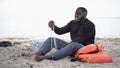 Desperate black man crying on shore, refugee survived shipwreck, lost home