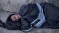 Desperate black man lying street covered with sleeping bag, poverty hopelessness Royalty Free Stock Photo