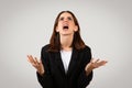 Desperate businesswoman in a black suit looking upwards with hands raised in exasperation Royalty Free Stock Photo