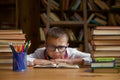 Desperate child sitting at desk table with lots of textbook in stack Royalty Free Stock Photo