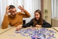 Desperate father and smiling daughter doing puzzle in living room at home Royalty Free Stock Photo