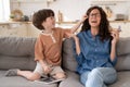 Frustrated helpless mother crying from anxiety with hyperactive little son sitting together on sofa Royalty Free Stock Photo