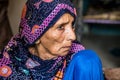 A desperate homeless refugee grandmother with sad expression and wearing blue dress