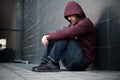 Desperate lonely man seated against the wall in the city