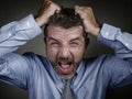 Desperate man in shirt and necktie suffering crisis screaming crazy feeling tired and overwhelmed isolated on studio background in