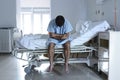 Desperate man sitting at hospital bed alone sad and devastated s Royalty Free Stock Photo