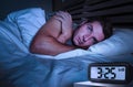 Desperate man in stress sleepless on bed with eyes wide opened suffering insomnia sleeping disorder depressed with digital alarm Royalty Free Stock Photo