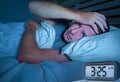 Desperate man in stress sleepless on bed with eyes wide opened suffering insomnia sleeping disorder depressed with digital alarm Royalty Free Stock Photo