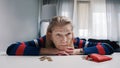 Desperate old woman pensioner looking at small amount of coins on the table