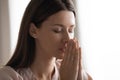 Religious young woman hold hands praying at home