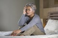 Dramatic lifestyle home portrait of attractive sad and depressed middle aged woman with grey hair on bed feeling upset suffering Royalty Free Stock Photo