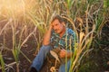 Desperate senior farmer standing in drought-damaged corn crop.