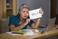Desperate and stressed attractive middle aged Asian woman holding notepad asking for help feeling overworked and exploited working Royalty Free Stock Photo