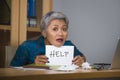 Desperate and stressed attractive middle aged Asian woman holding notepad asking for help feeling overworked and exploited working Royalty Free Stock Photo