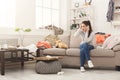 Desperate woman sitting on sofa in messy room