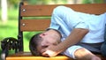 Desperate young male lying bench, depression symptom, drunk man in park, crisis